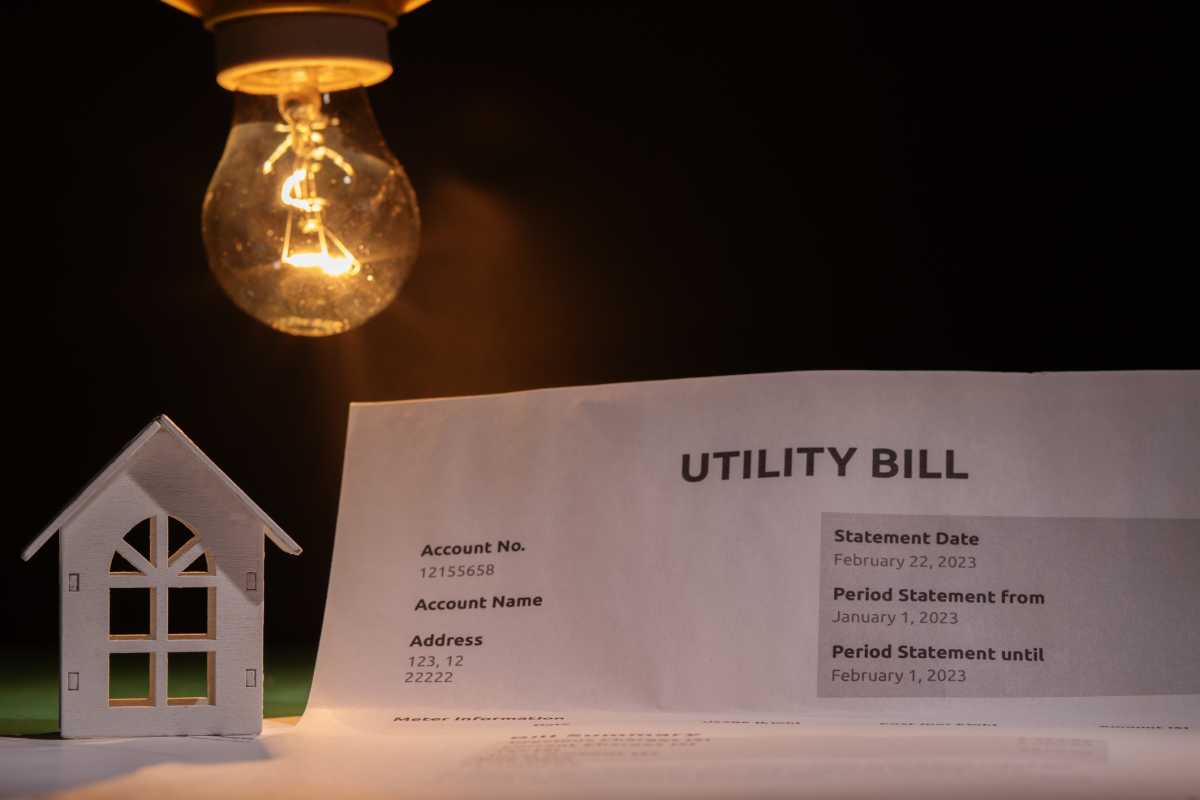 Utility bill and a house with a burning lightbulb, financial statement with cost breakdown, utility charges for electric power and heat, monthly budget planning