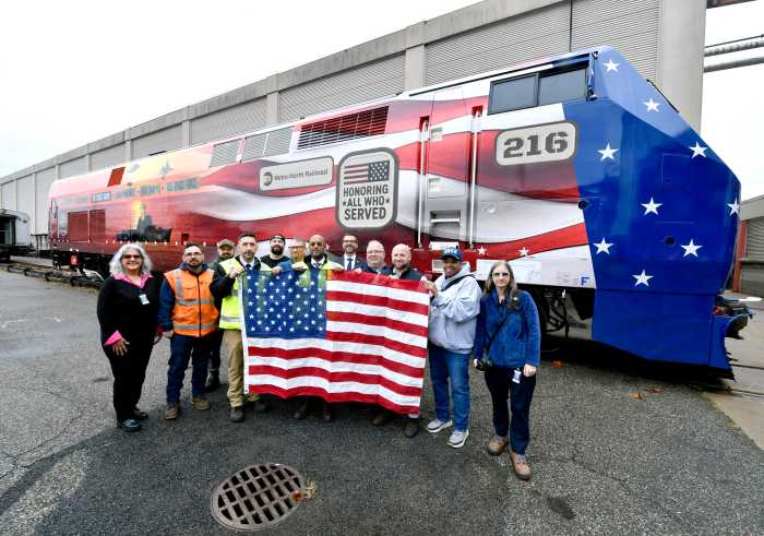 a group of people holding American flag next to a locomotive