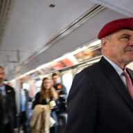 NYC Mayor's Race: One more ride for the red beret, as Curtis Sliwa campaigns to the very end 6 man wearing a suit and red beret on a train