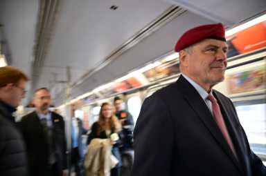 man wearing a suit and red beret on a train