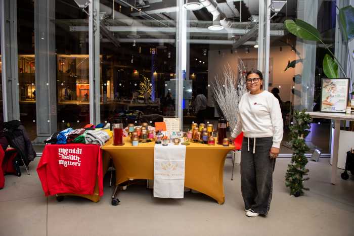 Columbia University Holiday Market supports Harlem businesses with free vendor space 17 woman in white shirt next to a table of merchandise