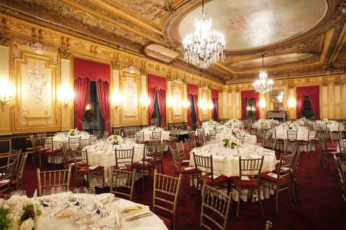 dinner tables set in an artisitic hall with red carpet