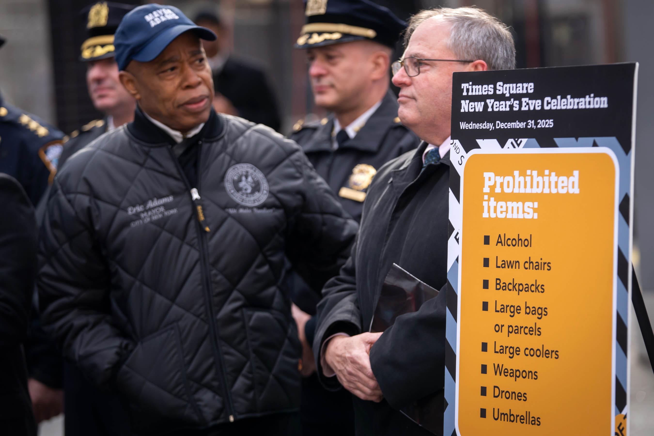 Mayor Eric Adams speaking in front of sign listing items banned from Times Square