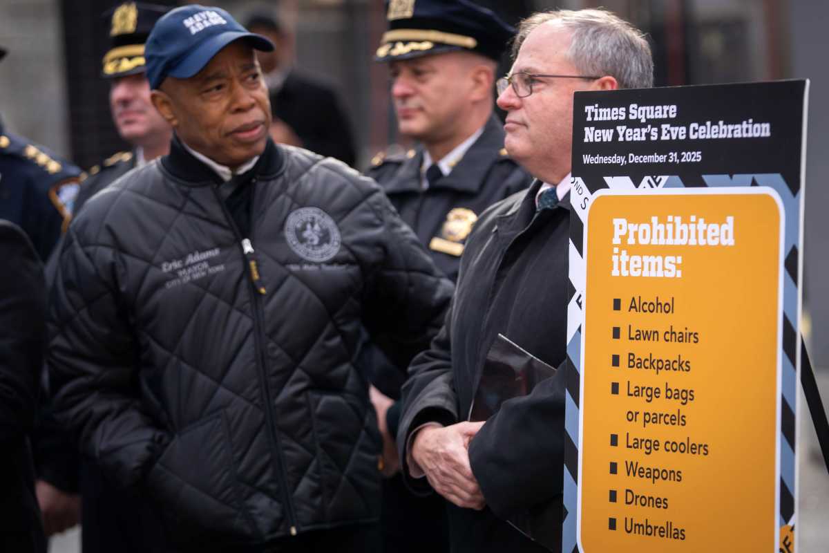 Mayor Eric Adams speaking in front of sign listing items banned from Times Square