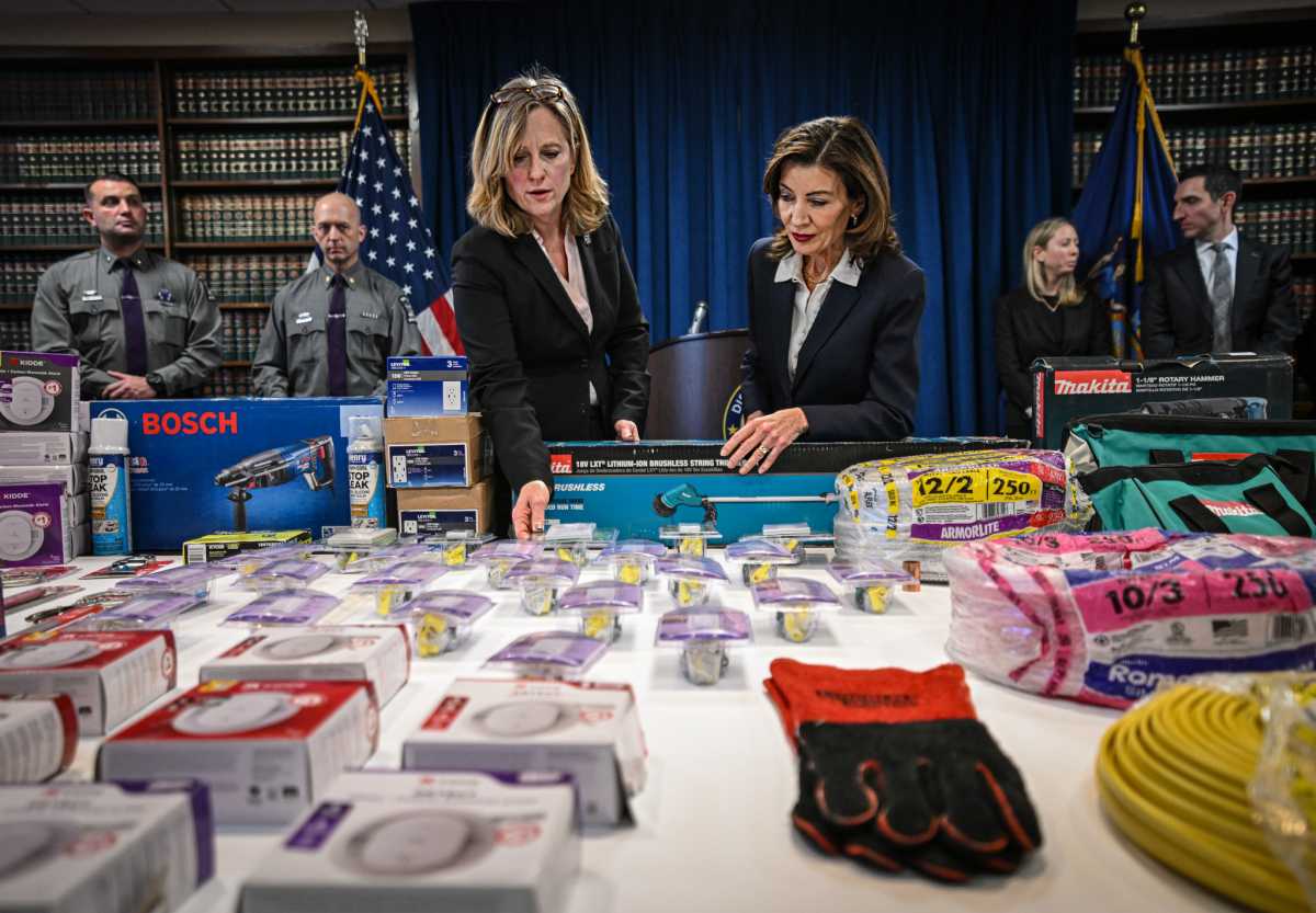 Queens DA Melinda Katz and Gov. Kathy Hochul look at table of stolen merchandise from Home Depot