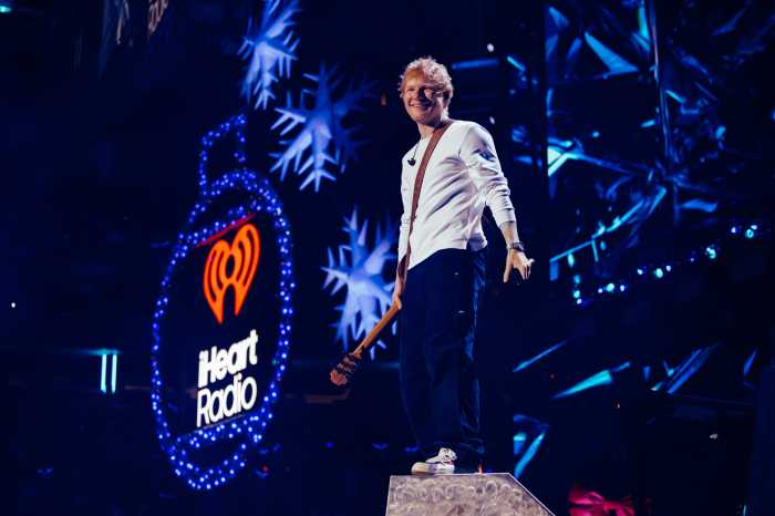 ed sheeran at jingle ball. man on stage holding a guitar