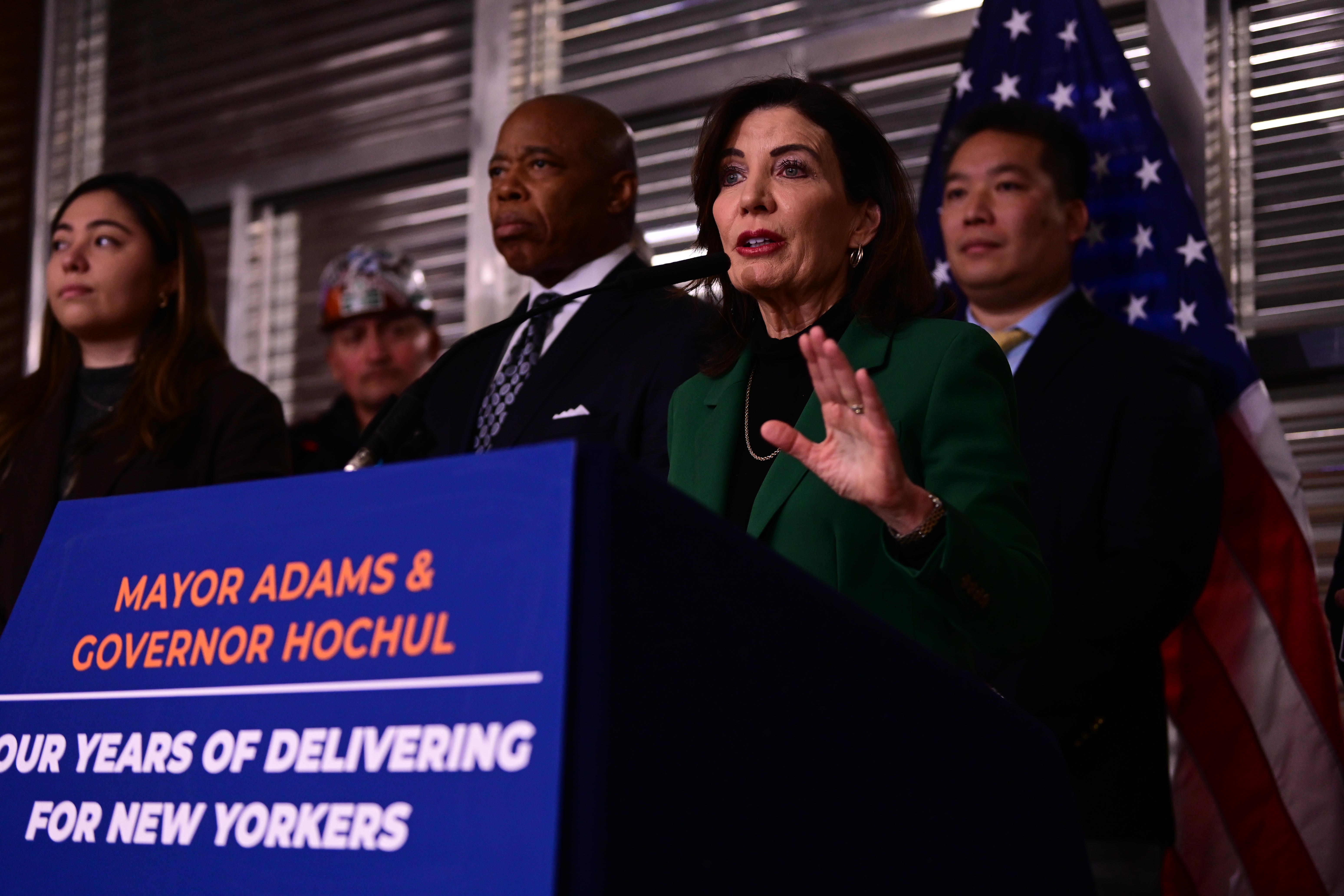 group of people standing at a podium that has a blue sign