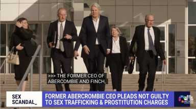 Ex-Abercrombie CEO Michael Jeffries walks out of the Central Islip federal courthouse wearing a suit with other suited men on either side of him.