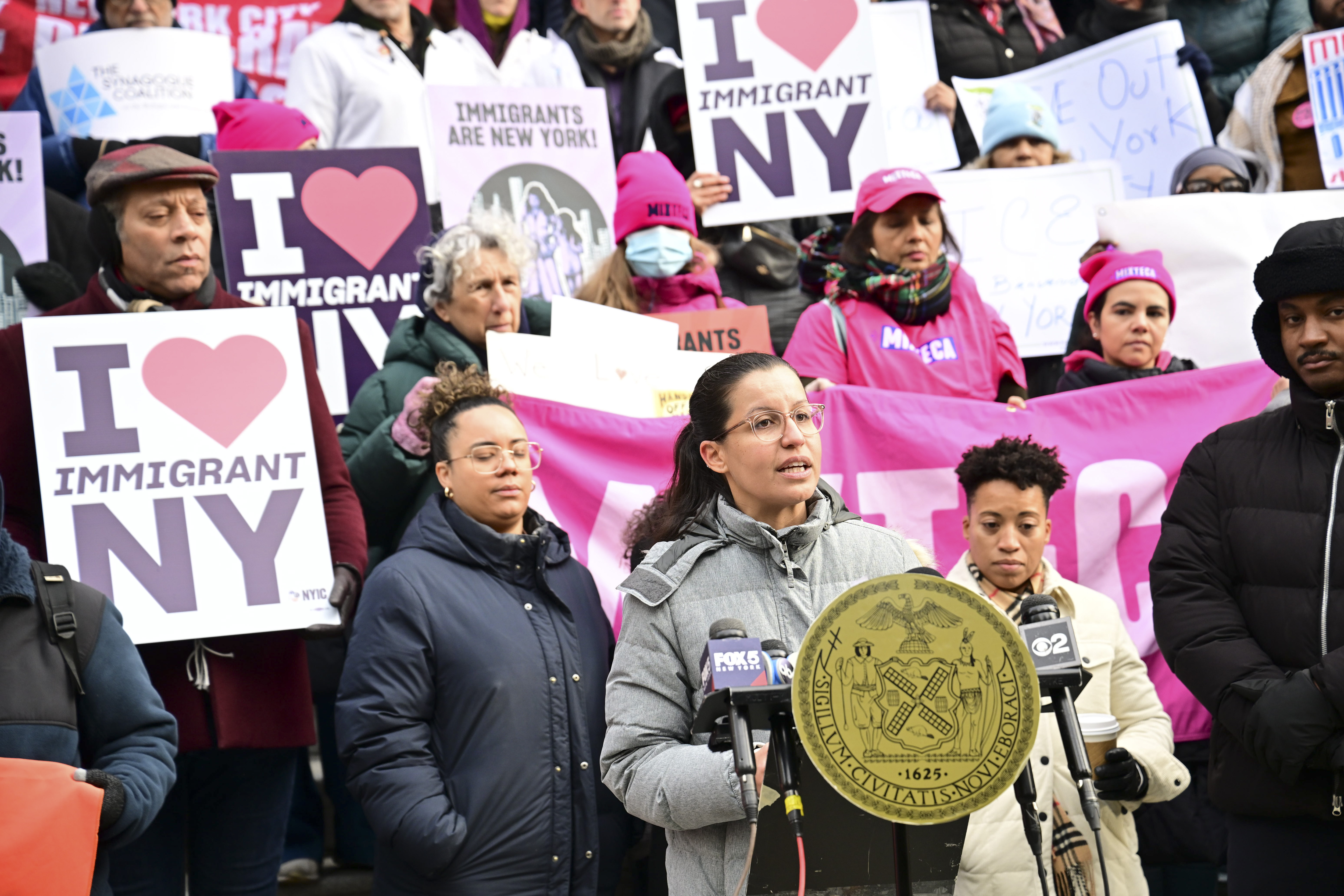 people ouside on stairs holding signs and wearing coats