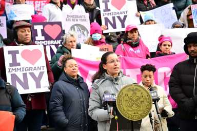 people ouside on stairs holding signs and wearing coats