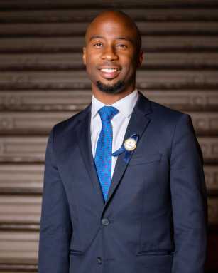 man wearing dark suit and blue tie Kamar Samuels