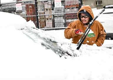 winter weather man clears snow from windshield