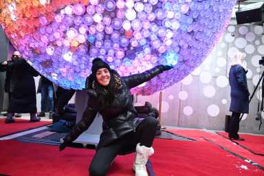 woman dressed in black in front of large crystal ball