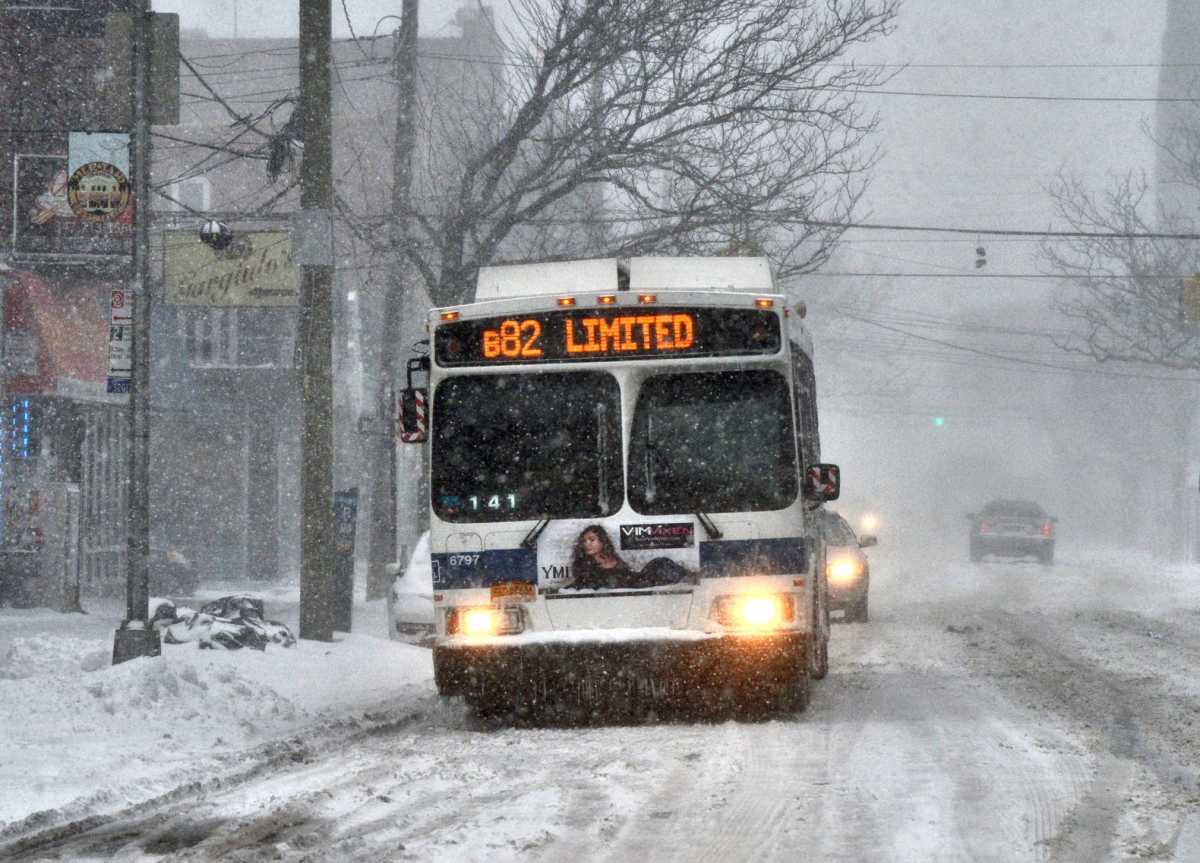 NYC bus traveling on snowy street during winter storm