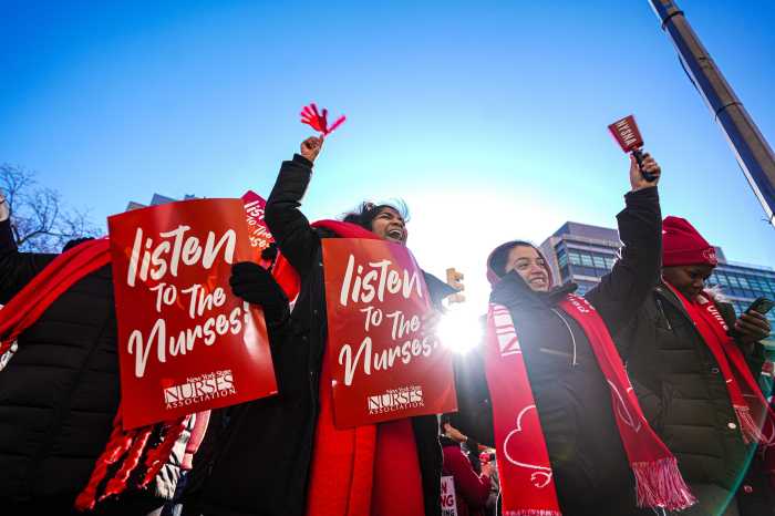 people wearing red clothes and holding red signs during the nurses strike in NYC