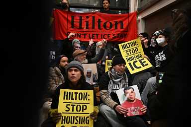 Anti-ICE demonstrators hold signs while occupying Hilton hotel