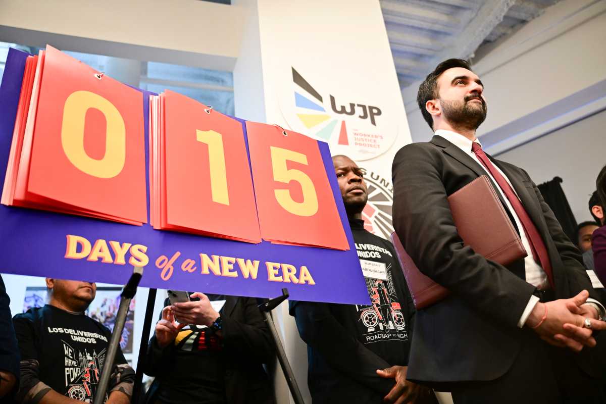 Mayor Zohran Mamdani speaking in front of sign