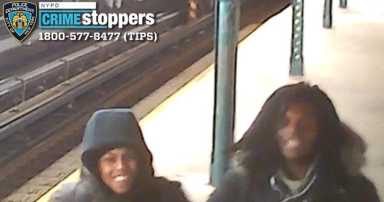 two peple wearing dark clothes in a subway station