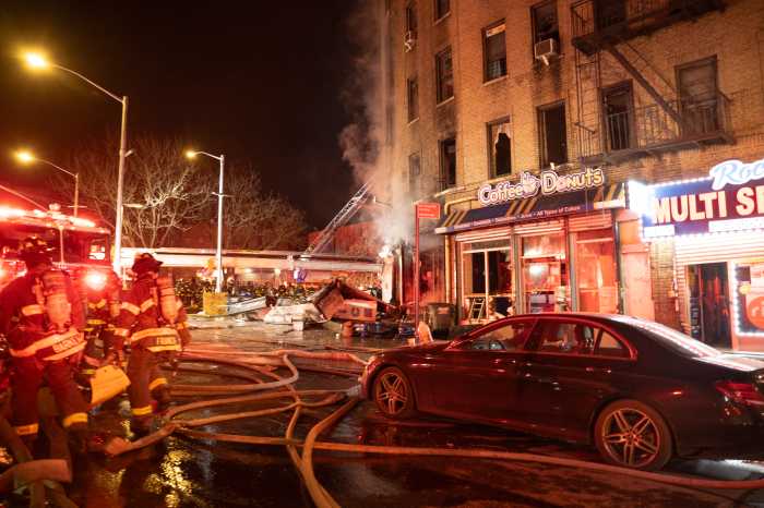 firefighters prepare hoses to fight a fire at night