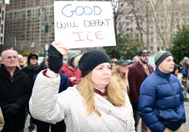 woman wearing a white coat holding a sign in NYC