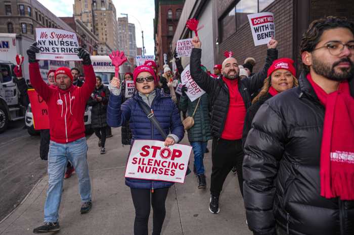 group of people outside holding signs supporting the nurses strike in NYC