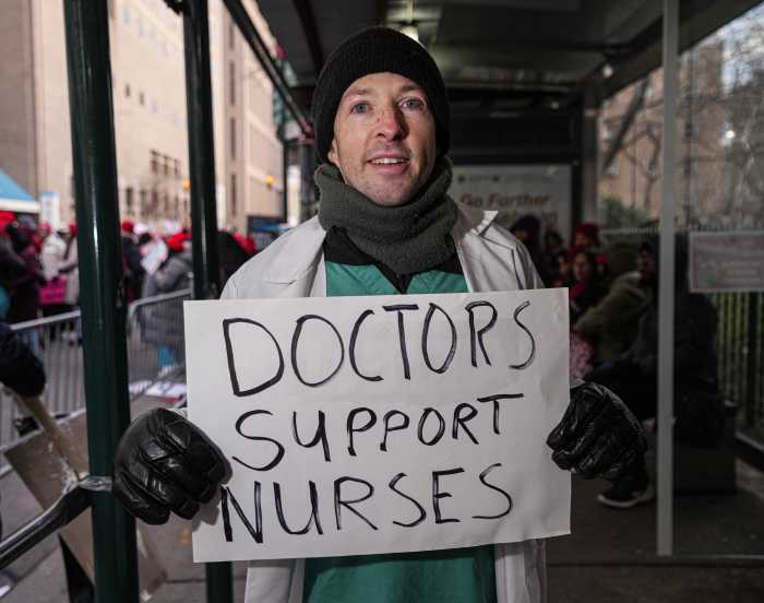 a man holding a sign during the nurses strike in NYC