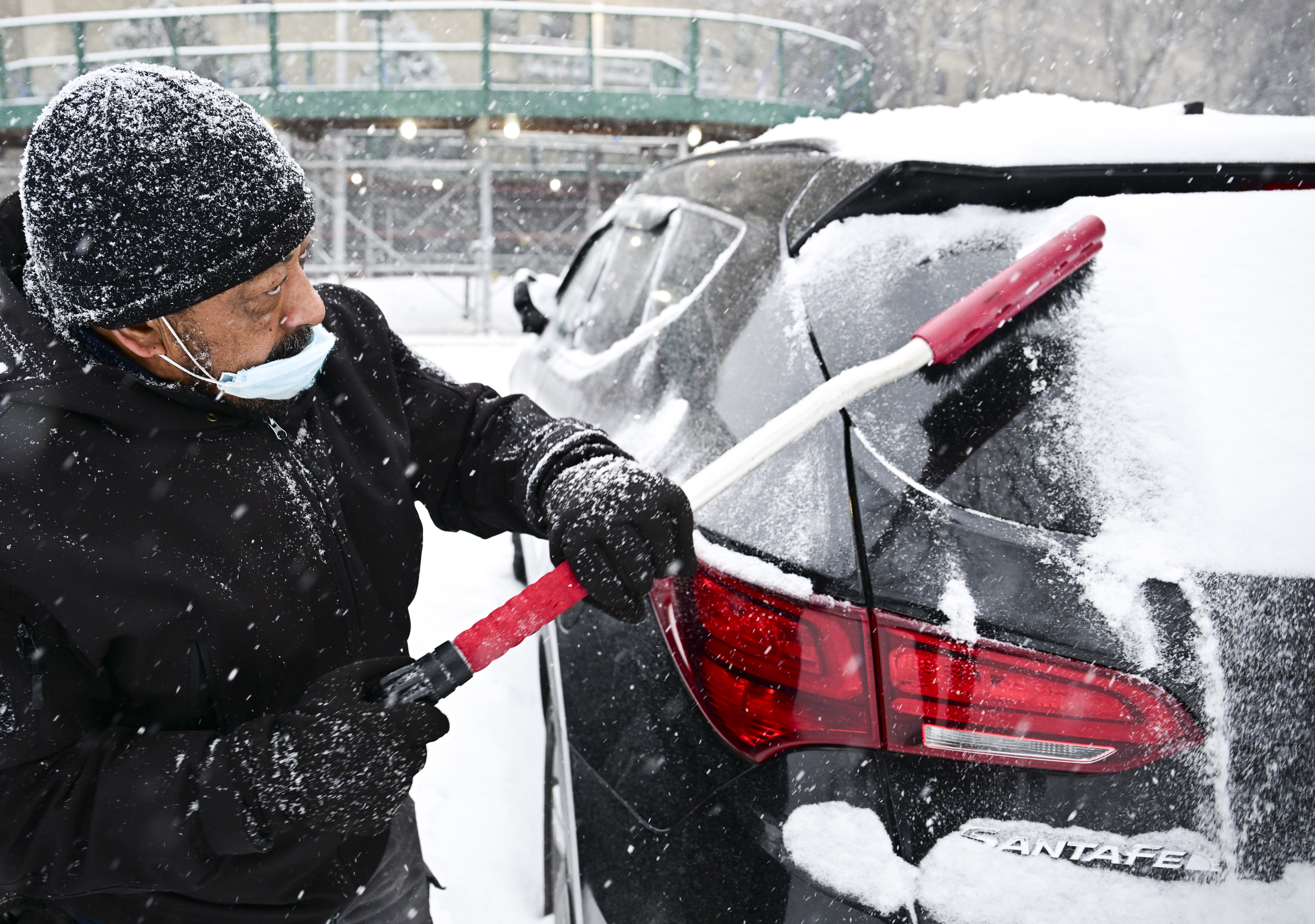 winter storm man clears snow off windshield of car