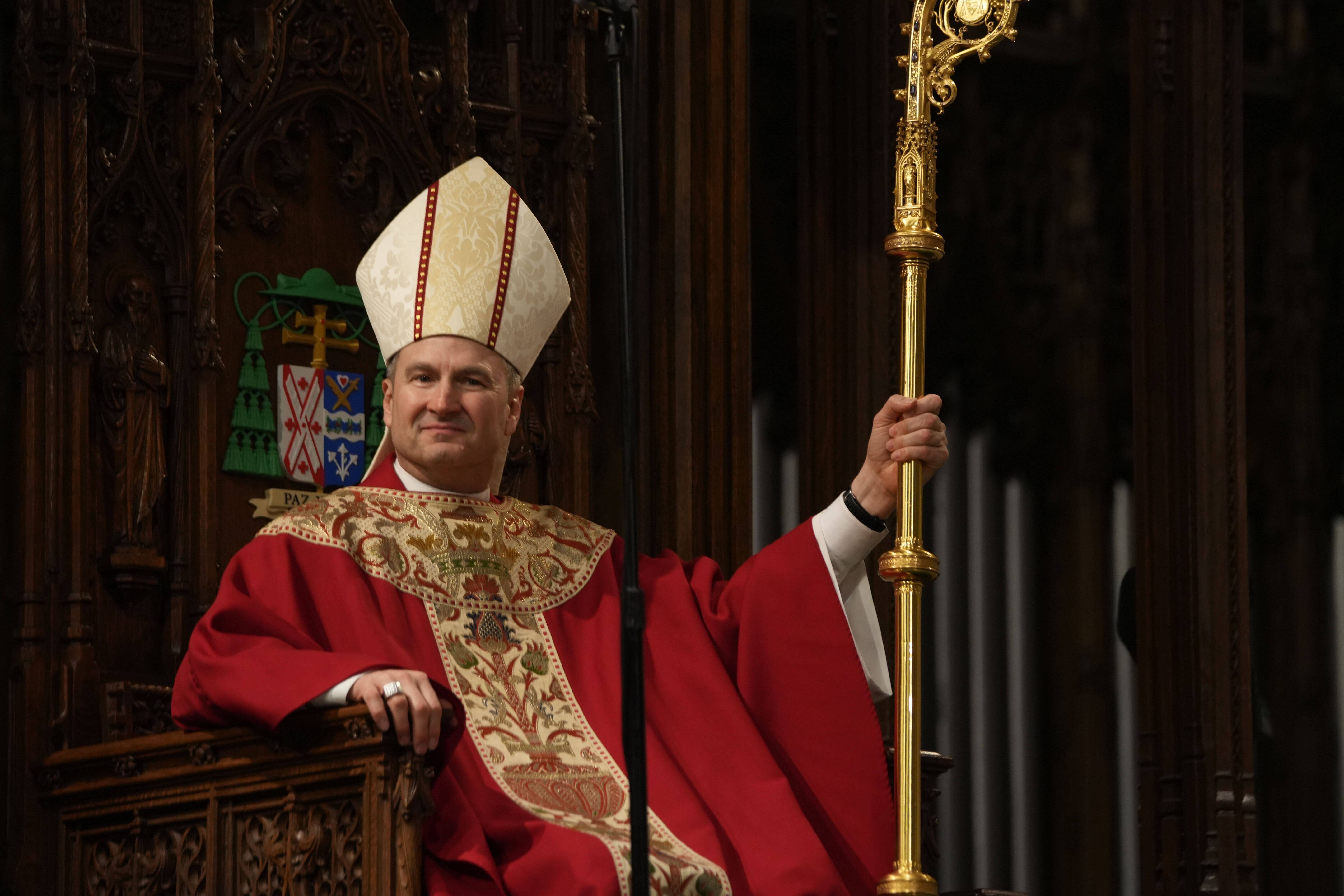 Archbishop Ronald Hicks sitting on altar with crozier