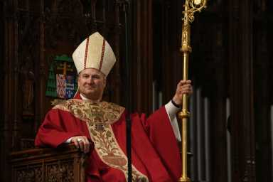 Archbishop Ronald Hicks sitting on altar with crozier