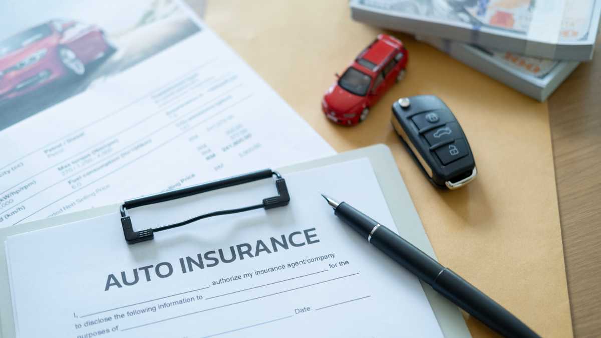Car insurance document with pen and car key on desk, symbolizing financial transaction for vehicle purchase and protection plan.