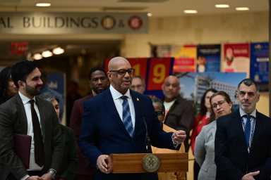 two men, including Mayor Mamdani, wearing suits at a podium