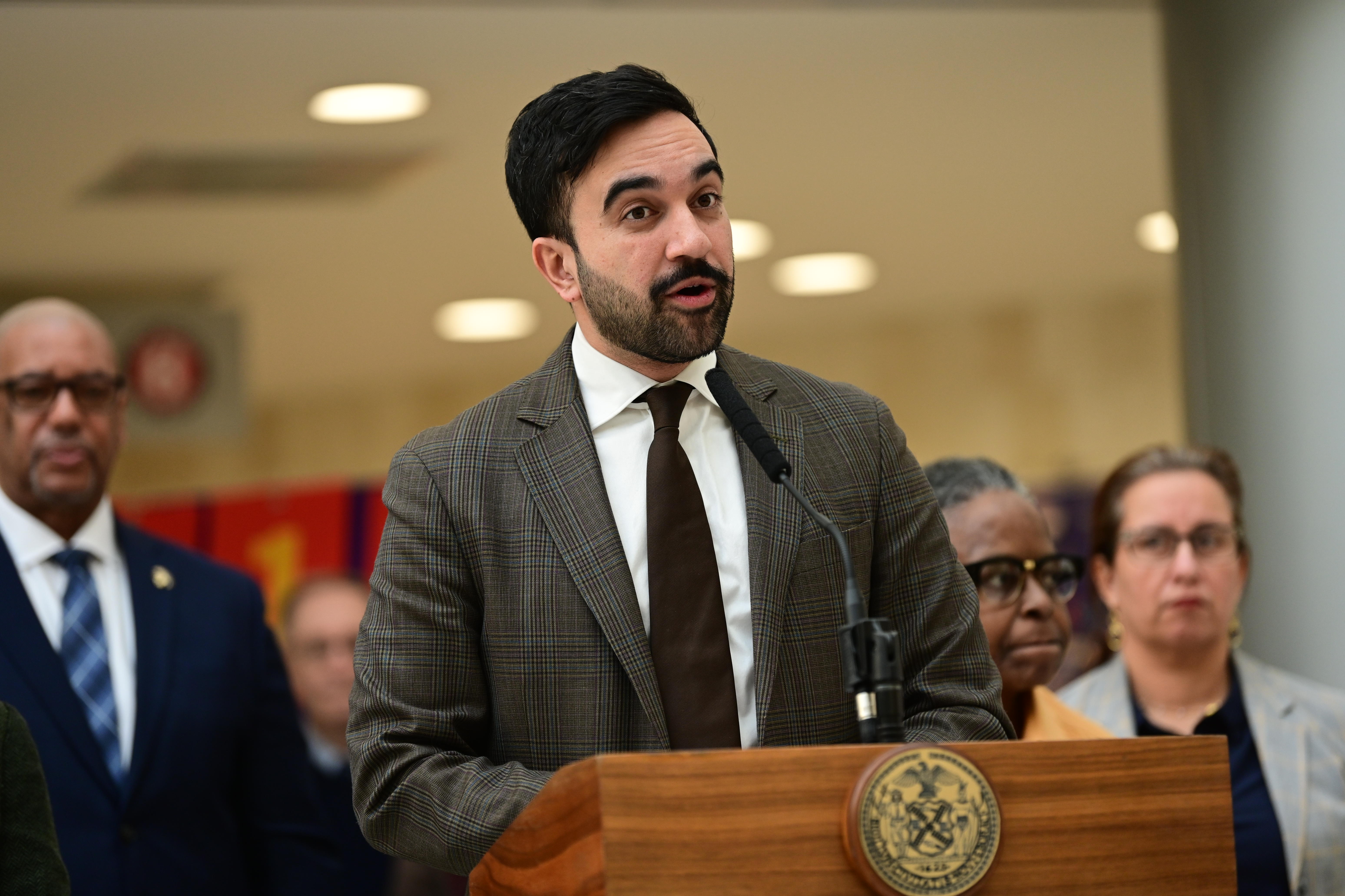 Mayor Mamdani in a suit at a podium