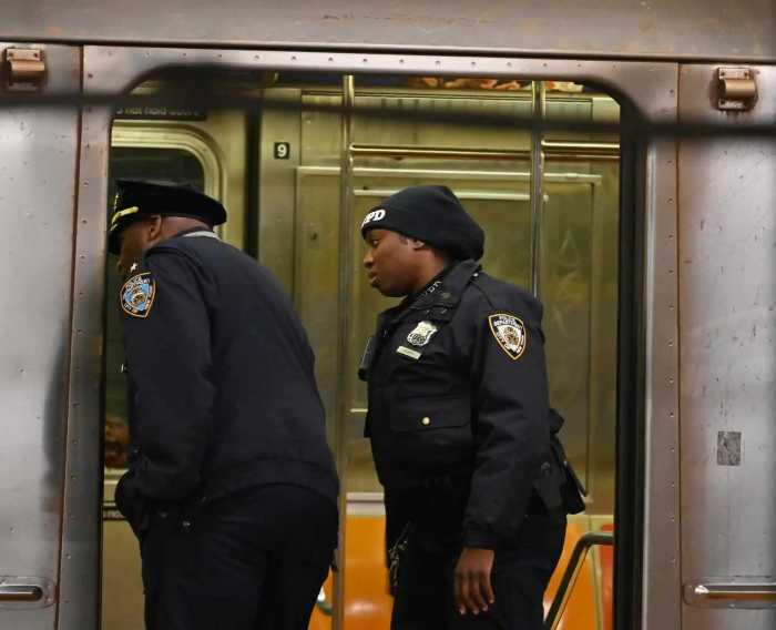FILE - Two police officers investigate a crime scene in a subway car.