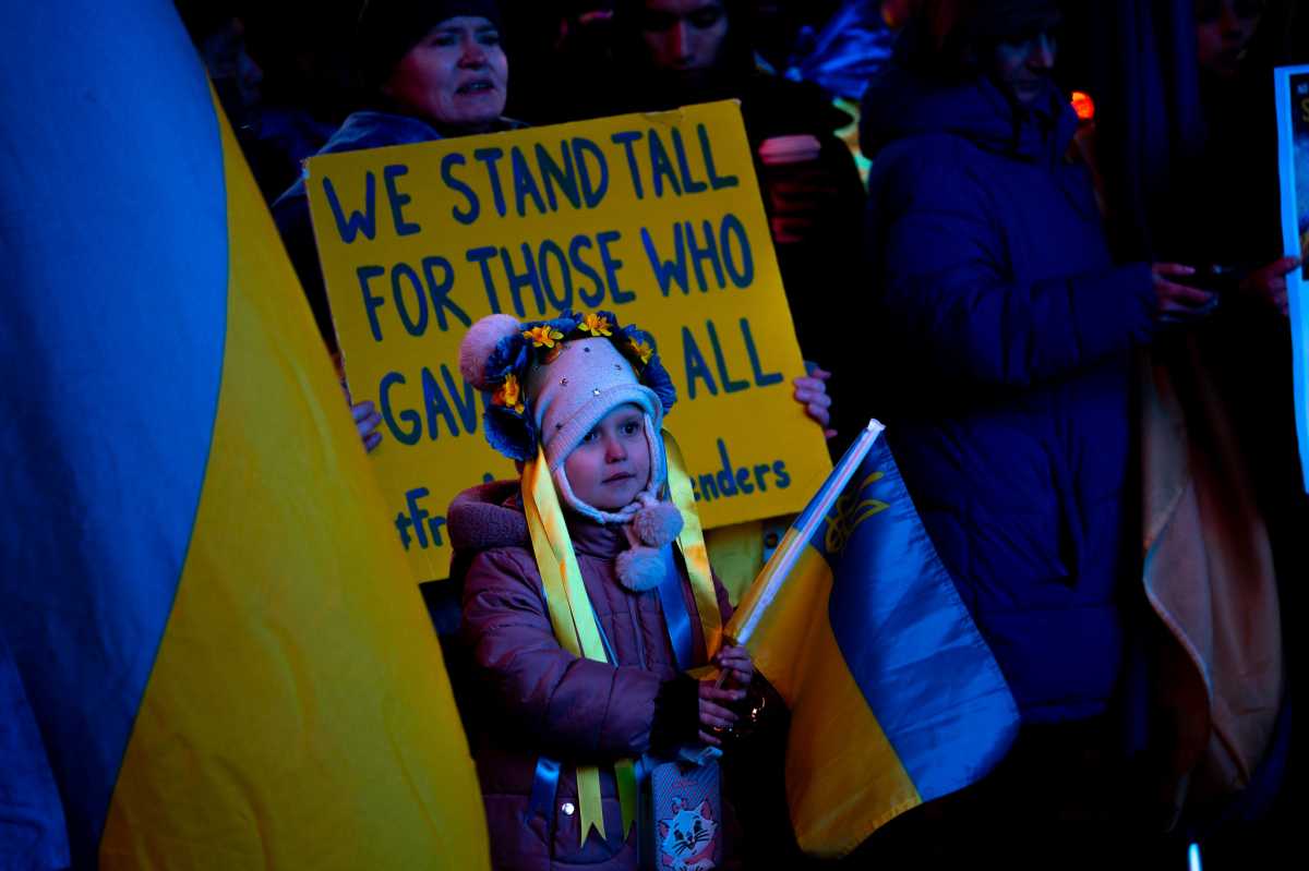 girl holds Ukraine flag at Times Square memorial on anniversary of invasion