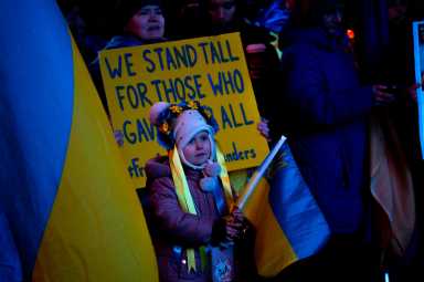 girl holds Ukraine flag at Times Square memorial on anniversary of invasion